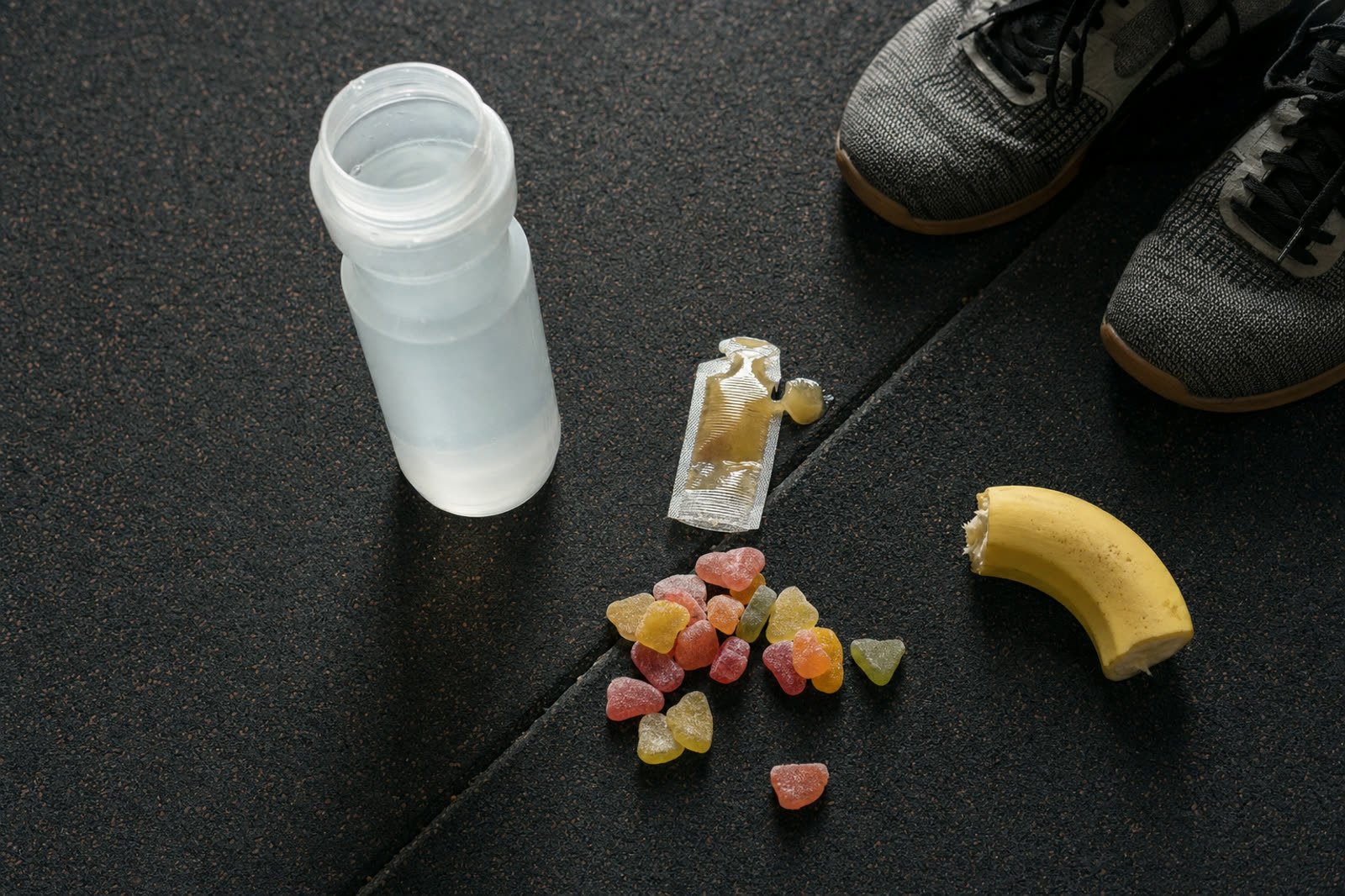 Bidón, gel energético, gominolas y medio plátano en el suelo de un box, opciones para tomar durante el entrenamiento